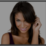 Smiling young woman with long dark hair and blue eyes.