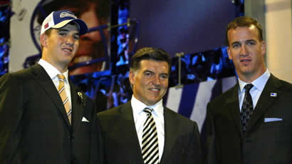 Three men in suits smiling at an event with blue lighting.