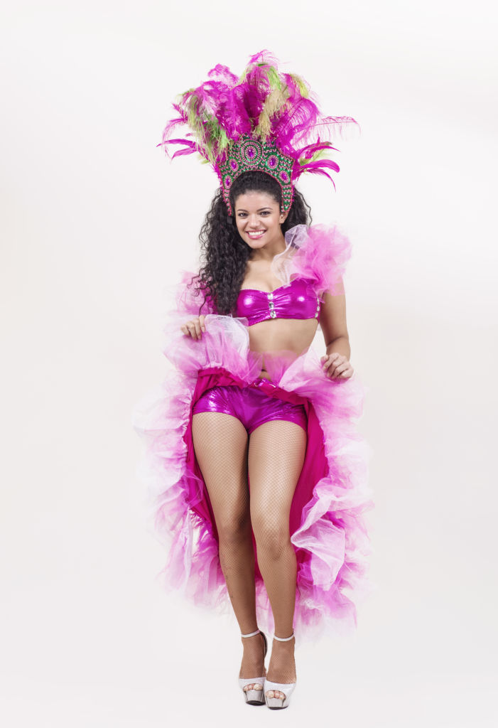 A woman in vibrant pink carnival costume with feathers and sequins.