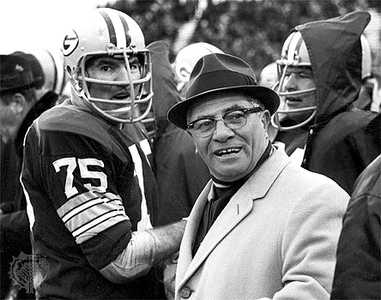 Historic football coach with players in vintage gear.