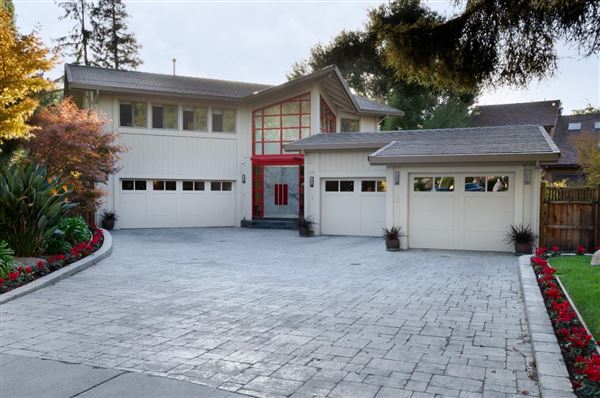 Modern house with a spacious driveway and red front door.