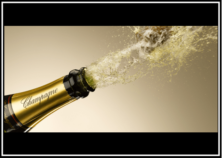 Champagne bottle popping with sparkling liquid bursting out.