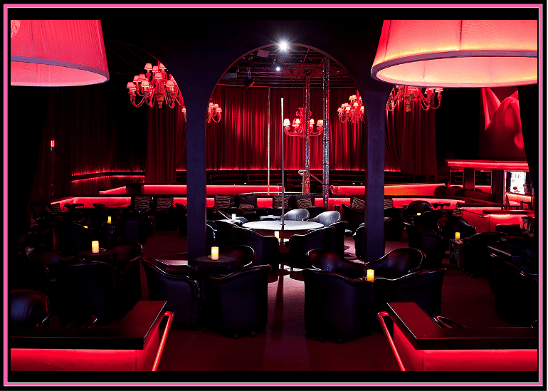 Luxurious nightclub interior with red and black decor and ambient lighting.