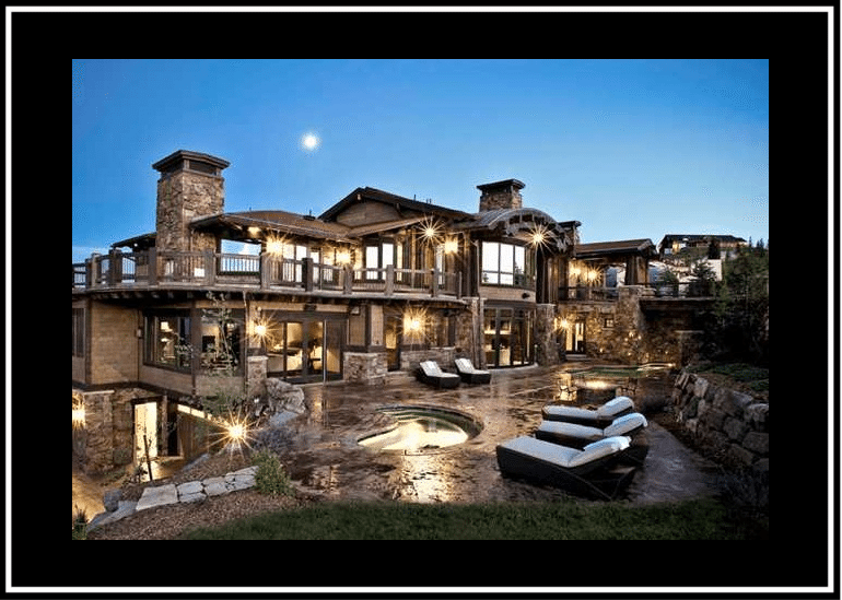 Luxurious modern house with large windows and outdoor pool at dusk.